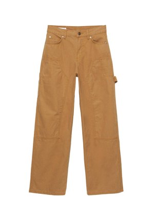 Osoba w szerokich brązowych spodniach i różowo-szarej pasiastej bluzce z długim rękawem, stojąca ze skrzyżowanymi rękami na białym tle.