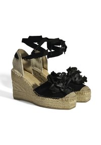 Schwarze Wildleder-Wedge-Espadrilles mit einer geflochtenen Jutesohle, schwarzen Riemen am Knöchel und stofflichen Blütenakzenten im Bereich der Zehen.