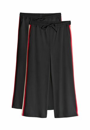 Shorts noirs en tissu lisse avec une taille élastique et un cordon de serrage, présentant des rayures latérales rouges et crème.