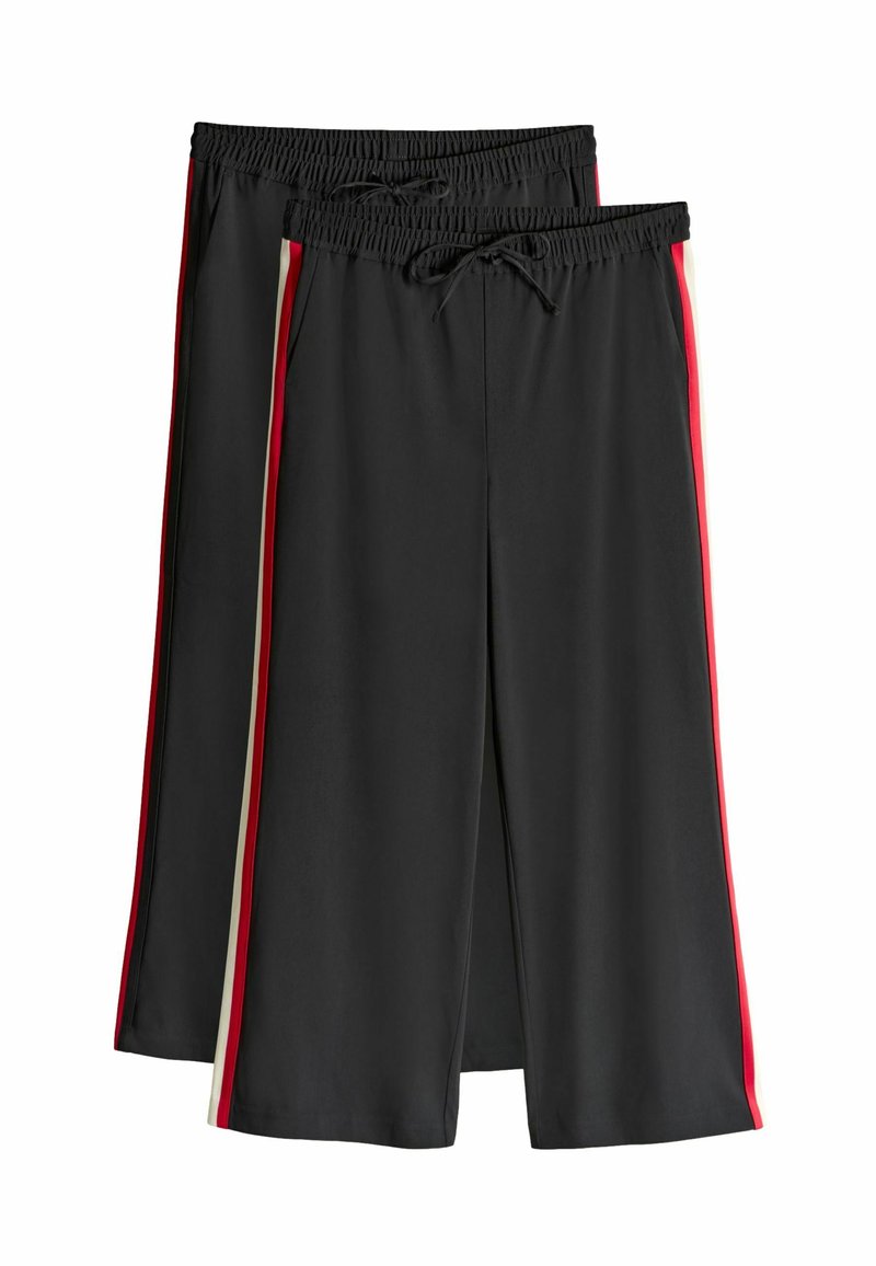 Mustat shortsit, jotka on valmistettu sileästä kankaasta, joustavalla vyötäröltä ja nauhalla, joissa on punaiset ja kermanväriset sivuraidat.