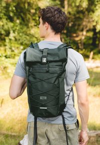 Fekete, felgöngyölhető hátizsák állítható pántokkal, elülső cipzáras zsebbel, bungeezsinóros részletekkel és hátsó címkével. Tartós szövetből készült.