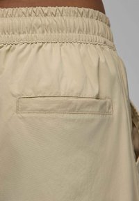 Beżowe szorty z elastycznym pasem i płaską tylną kieszenią. Gładki, lekki materiał o subtelnej fakturze. Szczegóły w klasycznym kroju.
