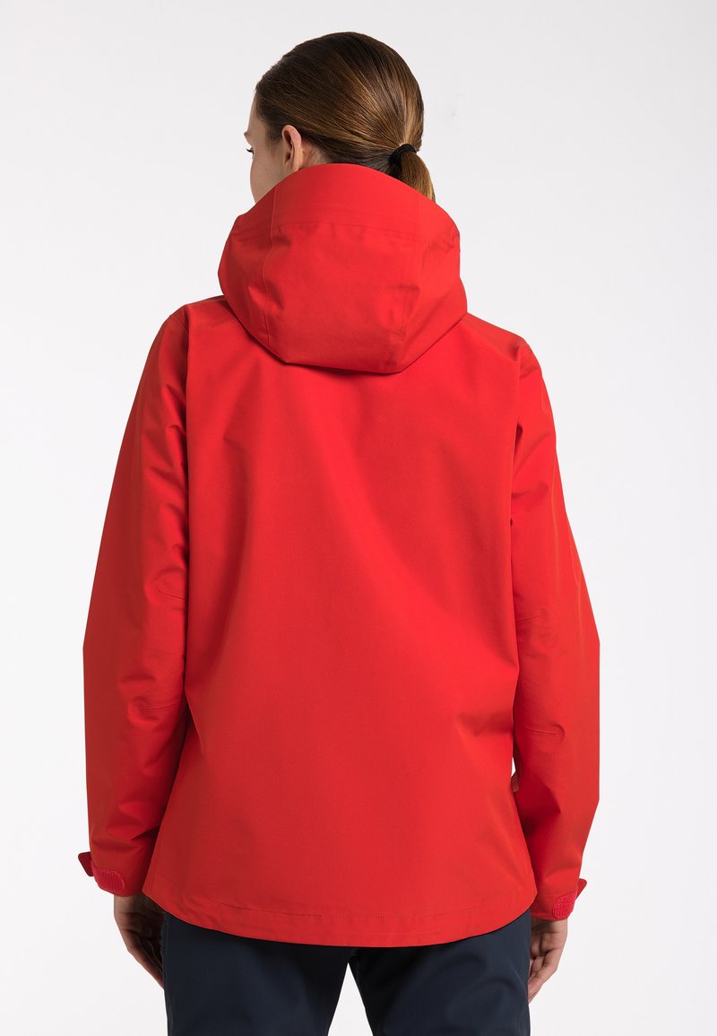 Červená voděodolná bunda s kapucí, hladký povrch, volný střih a nastavitelné manžety. Bez viditelných vzorů nebo kovových detailů.
