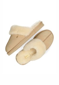 Pantoufles beiges à enfiler avec un extérieur en daim texturé et une doublure crémeuse douce et duveteuse. Dotées d'une semelle en caoutchouc et d'une semelle intérieure avec une marque.