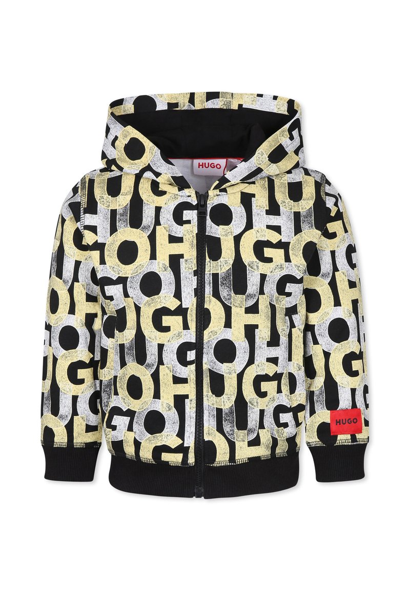 Sweat à capuche zippé noir, avec de grandes lettres graphiques jaunes et blanches. Étiquette rouge "HUGO" sur le devant. Texture douce, poignets côtelés.