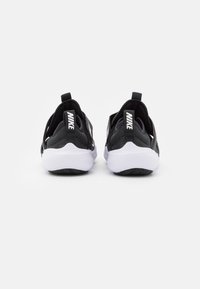 Black Nike sneakers featuring a slip-on design, textured fabric, and white soles with black detailing. Prominent Nike branding on heel.