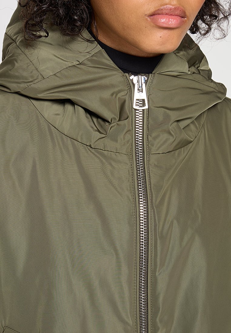 Olivengrüne Jacke mit hohem Kragen, Reißverschluss und gerafftem Stoff an der Kapuze, aus glattem, leichtem Material gefertigt.