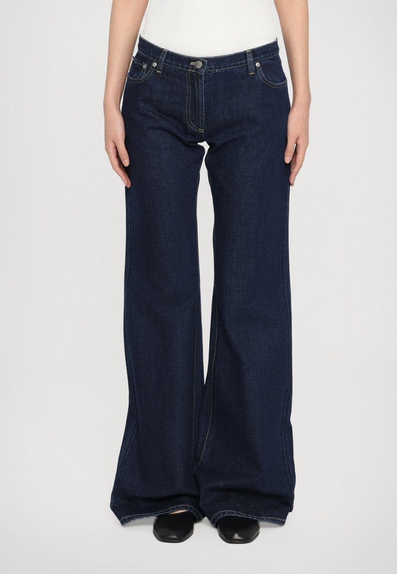 Vide ben bukser i mørkeblå denim med en glat overflade, der har en knaplukning, for- og baglommer samt synlige sømadetails.