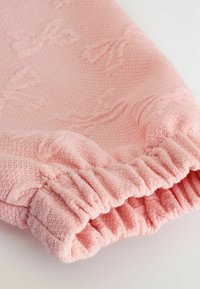 Rippstrick-Pulloverstoff in Pink mit einer weichen, strukturierten Oberfläche. Verfügt über einen elastischen Bund mit gerafftem Detail und dezenter Musterung im gesamten Stoff.