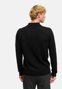 Maglione polo lungo nero con lavorazione a maglia texture, colletto e polsini a coste, caratterizzato da una silhouette aderente e dettagli sul bordo laterale.