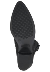 Suela de zapato negra con un agarre de goma texturizada, que presenta una forma triangular, un logo discreto, una marca de tamaño y una sección lisa y pulida.