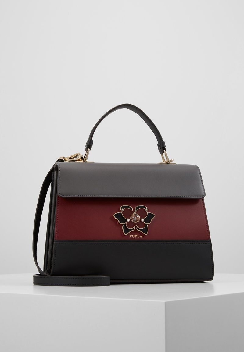 Sac à main en cuir structuré avec des panneaux noirs, rouge foncé et gris, doté d'une fermeture florale et d'une poignée supérieure avec une bandoulière amovible.