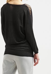 Czarny sweter dziany z długimi rękawami, z poziomymi wycięciami na ramionach i teksturowanym wykończeniem. Gładki i dopasowany w talii.