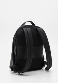 Black backpack featuring a textured leather body with mesh accents, padded shoulder straps, and a zippered pocket for storage.