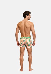 Boxershort met een print van groene avocado's op horizontale oranje en witte strepen, met een groene elastische tailleband met het label "MR K".
