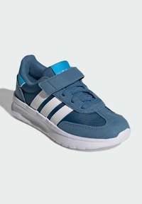 Modré tenisky s hornou časťou vyrobenou zo syntetického materiálu, bielym dizajnom s tromi pruhmi, suchým zipsom a polstrovanou podrážkou. Hladké a textúrované materiály.