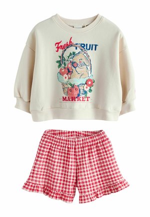 Cremefarbenes Sweatshirt mit Obstkorb und Schriftzug "Fresh Fruit Market", kombiniert mit rot-weiß karierten Shorts mit Rüschensaum.
