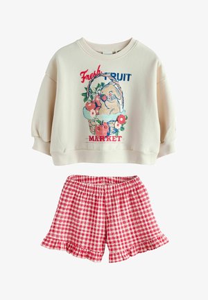 Sweatshirt crème avec panier de fruits et texte "Marché aux Fruits Frais", associé à un short à volants à carreaux rouges et blancs.