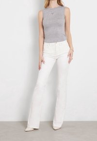 Gray sleeveless top paired with white flared jeans. The jeans feature a high waist and are made of denim, while the shoes are beige pointed heels.