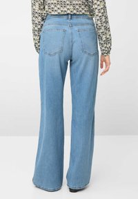 Jeans in denim azzurro chiaro a gamba larga con vita alta, caratterizzati da due tasche posteriori e una leggera texture. L'orlo è rifinito con una semplice cucitura.