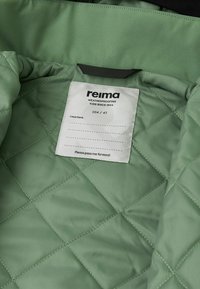 Fodera in tessuto trapuntato verde con un'etichetta bianca che mostra "reima WEATHERPROOFING KIDS SINCE 1944" e taglia 104/4T.