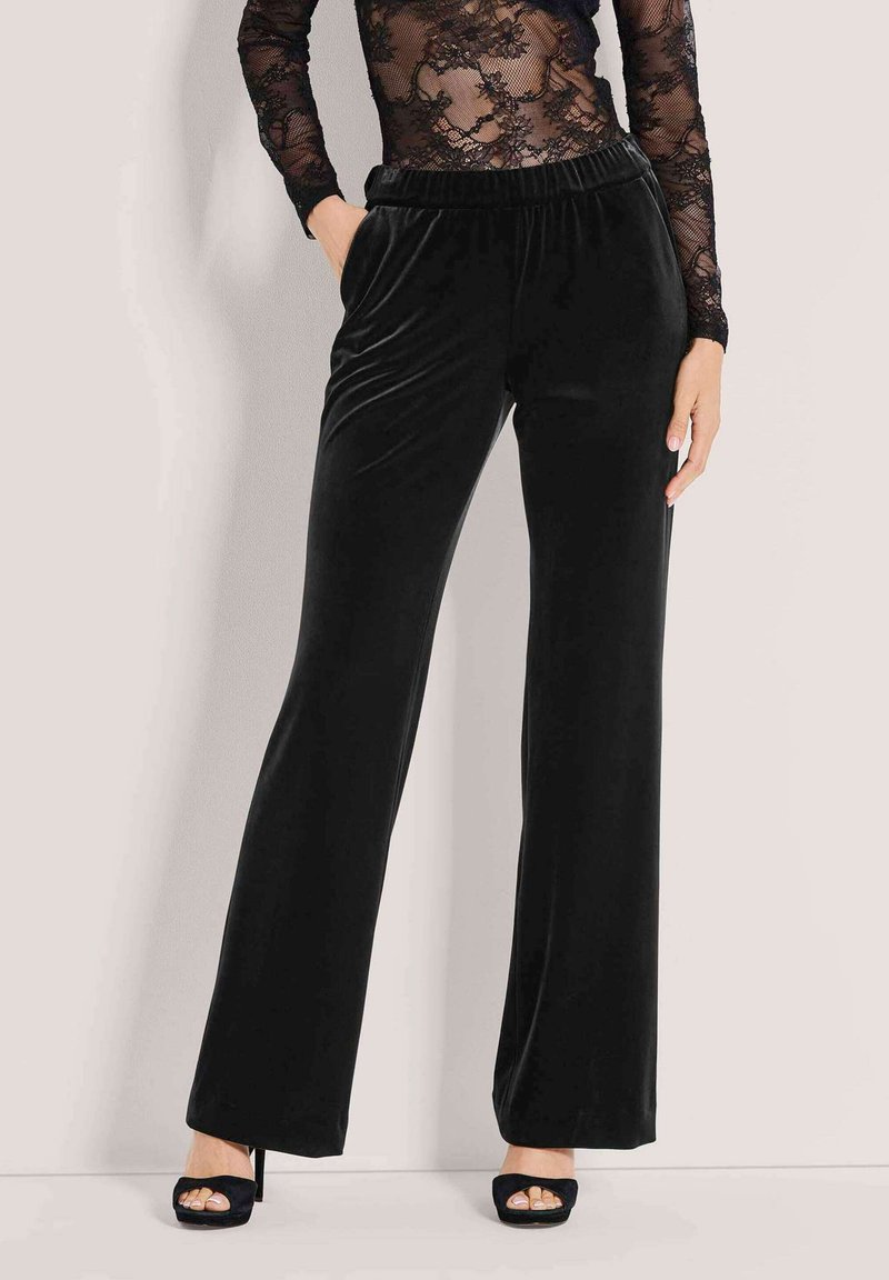 Zwarte fluwelen wijde pijpenbroek met een elastische tailleband, gekenmerkt door een soepele textuur en een casual silhouet, gecombineerd met open teen hakken.