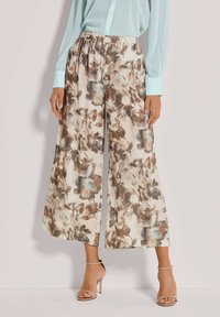 Floral wijde broek van lichte stof. Beige basis met bruine en blauwe bloemachtige patronen. Elastische tailleband voor comfort, met een losse pasvorm.