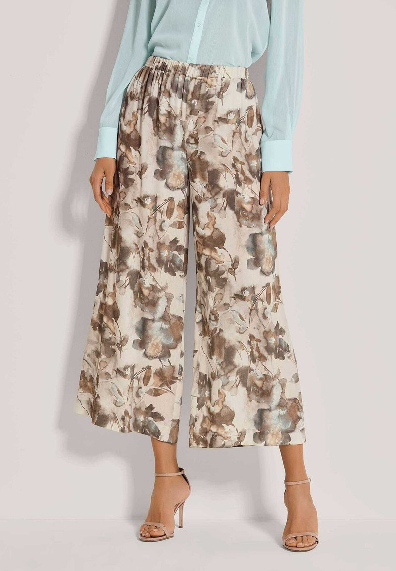 Floral wijde broek van lichte stof. Beige basis met bruine en blauwe bloemachtige patronen. Elastische tailleband voor comfort, met een losse pasvorm.