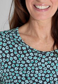 Schwarzes Blumenshirt mit rundem Ausschnitt, ausgestattet mit kleinen türkisfarbenen Blumen, die über den Stoff verteilt sind. Weicher Stoff mit leichtem Design.