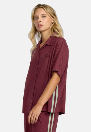 Bordeauxkleurig shirt met korte mouwen, een relaxte pasvorm, knoopsluiting aan de voorkant, geborduurde details en groene verticale strepen aan de zijkanten.