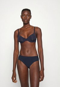 Marineblauwe beha en bikiniset gemaakt van gladde stof, met dunne verstelbare bandjes en een doorschijnende afwerking, met een simpel ontwerp zonder versieringen.