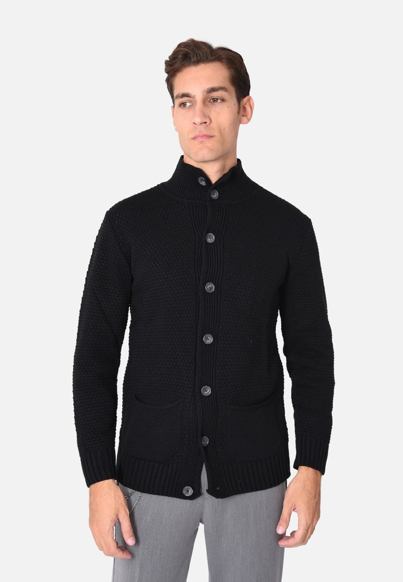 Cardigan lavorato a maglia nero con colletto alto, chiusura frontale a bottoni e due tasche anteriori. La texture è spessa, con polsini e orlo a coste.