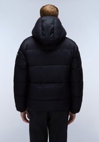 Giacca a vento nera con un grande cappuccio rotondo e cuciture orizzontali visibili. Tessuto liscio e materiale leggermente lucido.