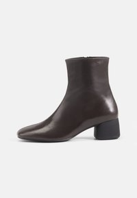 Brown leather ankle boot with a pointed toe and a block heel. Smooth texture, high shaft, and minimal hardware details.