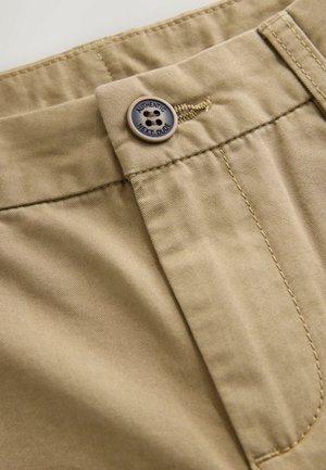 Beige bomuldsbukser med en glat tekstur, som har en knaplukning indgraveret med "AUTHENTIC NEXT DUDE" og pænt syede sømme.