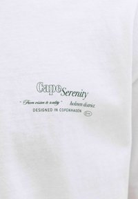 Weißer Stoff mit aufgedrucktem Text: "Cape Serenity", "Von der Vision zur Realität", "Holmen-Viertel" und "Entworfen in Kopenhagen".