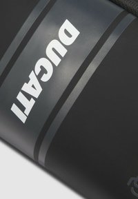 Bolso cilíndrico negro con el logo en relieve "DUCATI" en blanco. Cuenta con rayas grises, material resistente y una correa negra texturizada para mejor agarre.