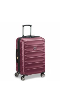Valigia rigida di un intenso color bordeaux, caratterizzata da un design a righe, una cerniera nera, quattro ruote girevoli e un manico estraibile.