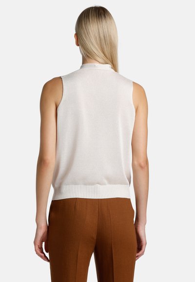 Top de punto sin mangas en crema con escote redondo y dobladillo acanalado, combinado con pantalones de pierna ancha marrones, mostrando una textura suave.