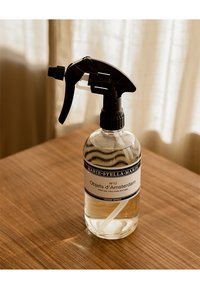 Klar glas sprayflaska med svart trigger, märkt "Objet d'Amsterdam," som innehåller en rumsspray med en ljus vätska och ett vitt sugrör.