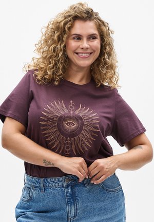 T-shirt bordeaux avec un graphique d'œil doré et un design d'ailes, fabriqué en tissu doux. Associé à un short en denim bleu taille haute, au style vintage.