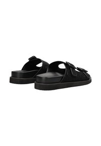 Zwarte slip-on sandalen met een gestructureerde bovenkant, uitgesneden details en dubbele gespaccenten op de banden, gemonteerd op een platte zool.