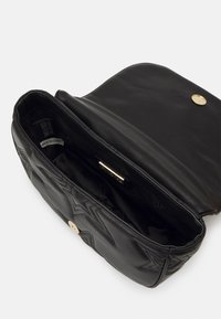 Sac à main en cuir noir avec un motif matelassé et des accessoires en or. L'intérieur ouvert présente une doublure lisse et une étiquette de la marque. Design plat.