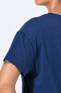 Námořnicky modré bavlněné tričko s kulatým výstřihem, krátkými rukávy a ohrnutými manžetami; hladká textura a volný střih.