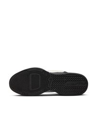 Suela de zapatilla negra con un patrón de agarre texturizado, que presenta un logotipo prominente y una construcción de goma. El borde resalta un contraste de color claro.