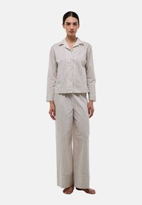 Ensemble de pyjama rayé en tissu doux. Chemise à boutons avec un col et des manches longues. Pantalon ample avec un large ourlet et une rayure contrastante.