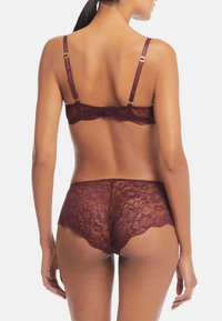 Burgundy spetsunderklädesset med ett delikat blommönster, justerbara band, guldfärgade detaljer och vågiga kanter.