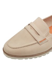 Beige semsket loafers med sømdetaljer, et dekorativt bånd og kontrasterende oransje aksent på siden. Hvit gummisåle.