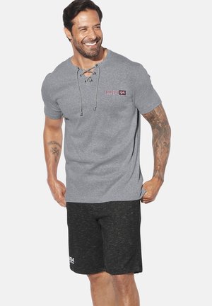 Graues Kurzarmshirt mit rundem Halsausschnitt und Schnürdetails, kombiniert mit schwarzen strukturierten Shorts mit einem Akzentlogo.