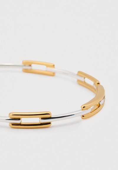 Metal bracelet featuring alternating gold and silver segments with a sleek, minimalist design. Notable accents include elongated links.